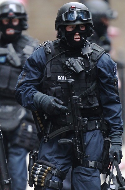 Armed police officers walk in Tottenham Court Road in central London April 27, 2012.  Police sent a hostage negotiator to an office block in central London and evacuated the area around the building after a man threw computer equipment from a fifth floor window on Friday.   REUTERS/Luke MacGregor